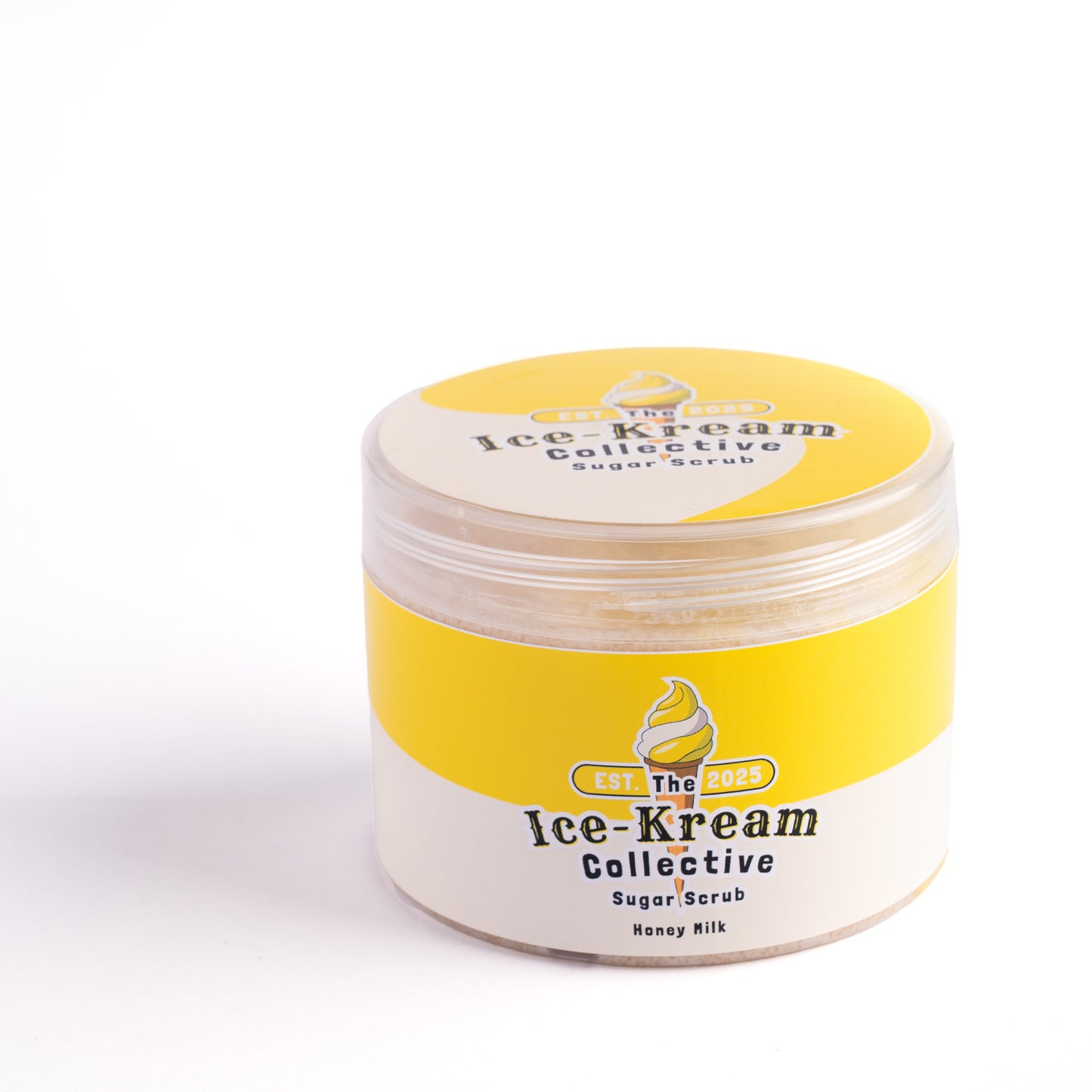 The Ice-Kream Collective Honey Milk sugar scrub in a round jar with yellow and cream packaging, labeled EST. 2025, on a white studio background.