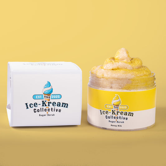 The Ice-Kream Collective Honey Milk sugar scrub in a clear jar with yellow and cream packaging, displayed next to its branded box on a pastel yellow background.