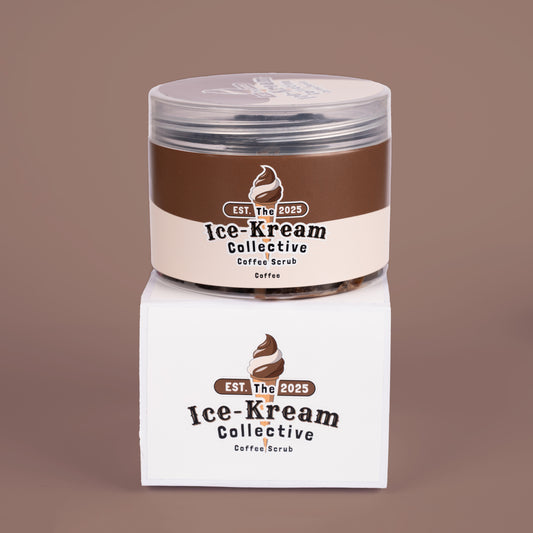 The Ice-Kream Collective coffee scrub in a clear round jar with brown and cream packaging, displayed on a branded box against a warm brown background.