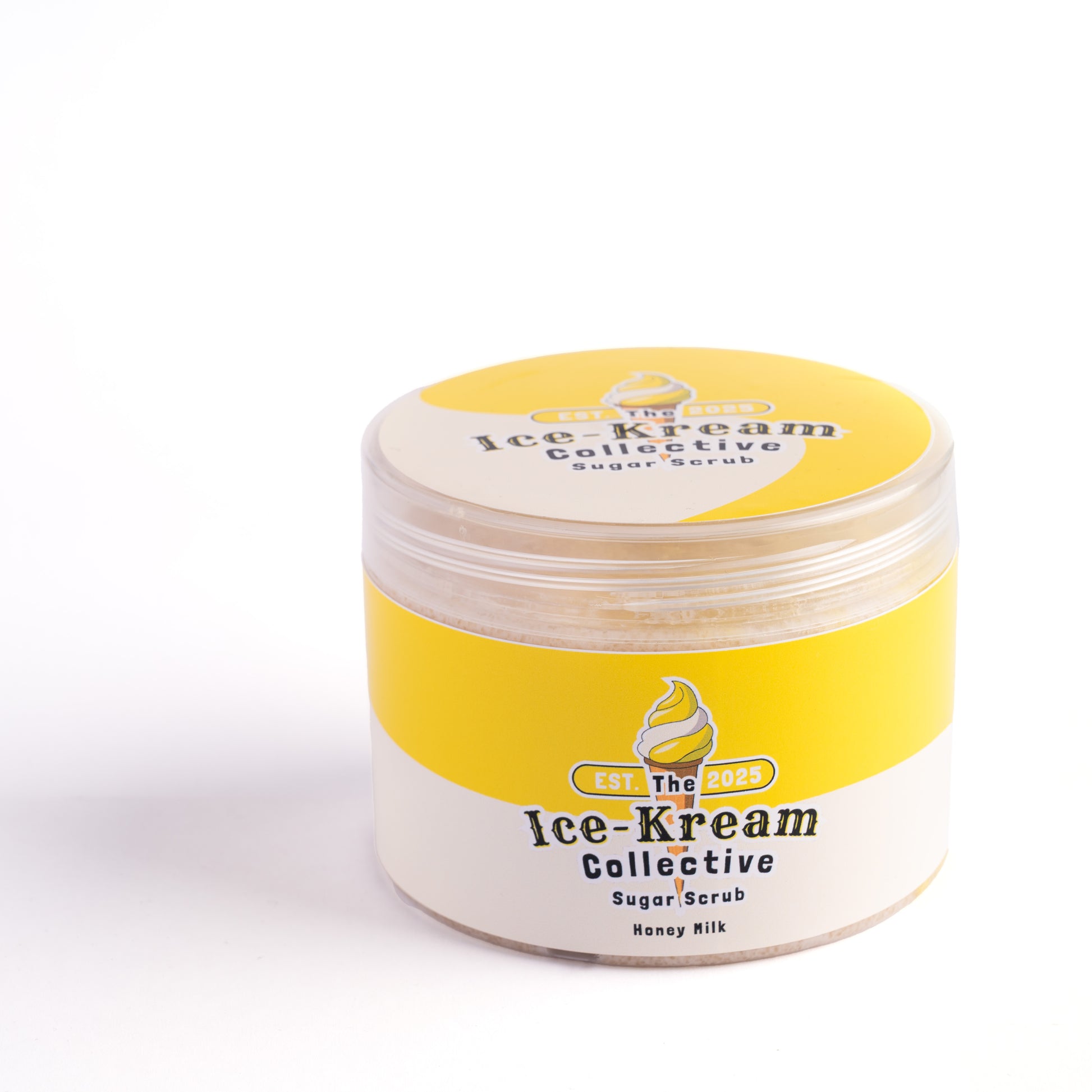 The Ice-Kream Collective Honey Milk sugar scrub in a round jar with yellow and cream packaging, labeled EST. 2025, on a white studio background.